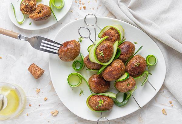 Spiedini di polpette di pane raffermo con capperi, olive, pomodori secchi e zucchine, cotte al forno